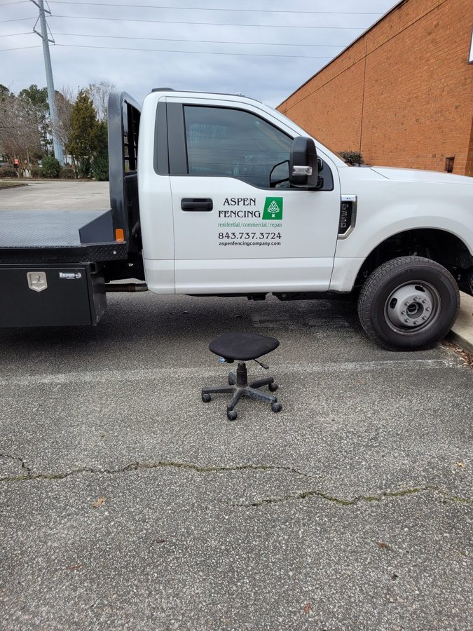 White 'Aspen Fencing' service truck with green door graphics and phone number