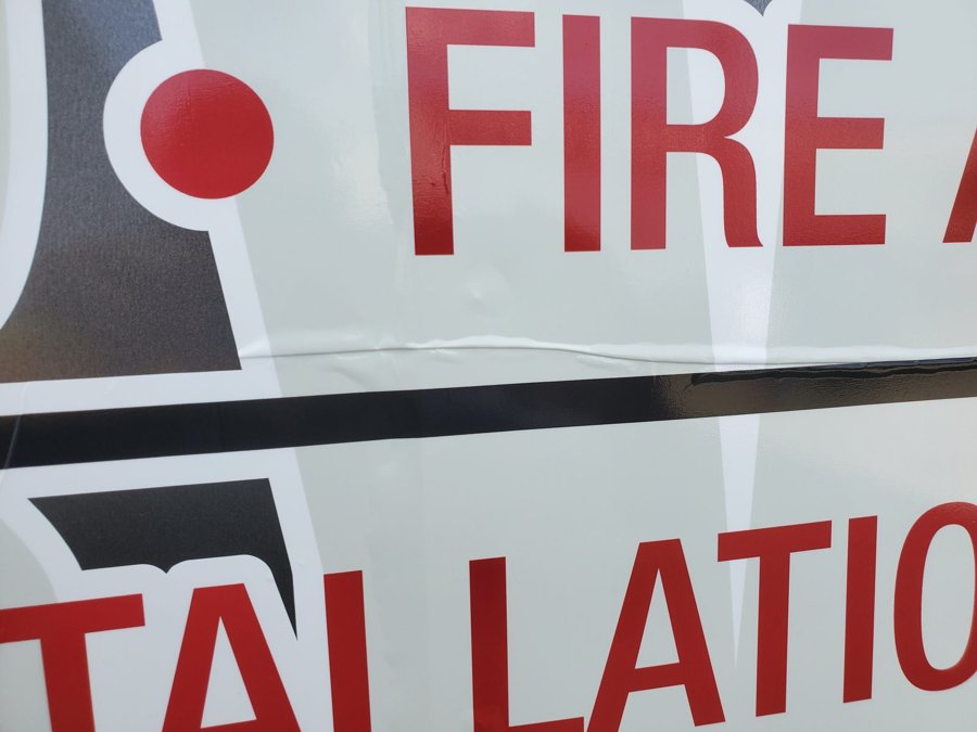 Close-up of red-and-white 'FIRE & LIFE SAFETY / INSTALLATION' side-panel vehicle graphics