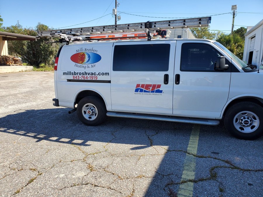 White 'Mills Brothers Heating & Air' service van with door graphics and ladder rack