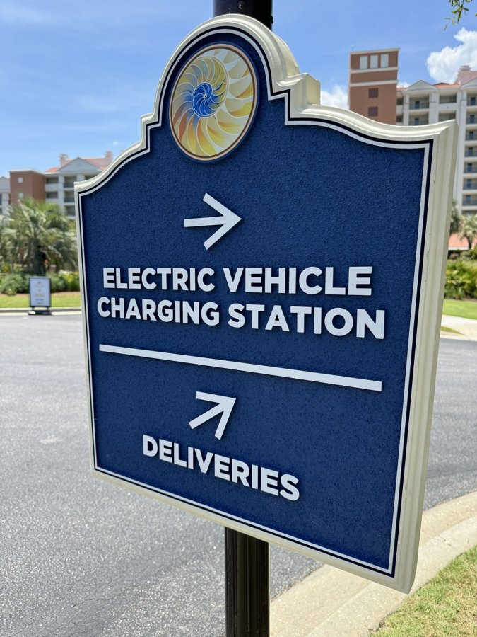 Navy 'ELECTRIC VEHICLE CHARGING STATION / DELIVERIES' wayfinding sign with brass detail