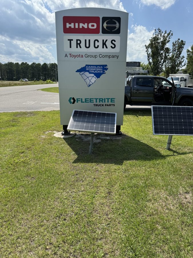 'HINO TRUCKS - A Toyota Group Company' pylon sign with integrated solar-panel power