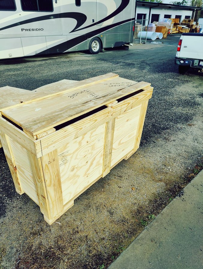 Custom wooden shipping crate palletized for freight, with client motorcoach in the background