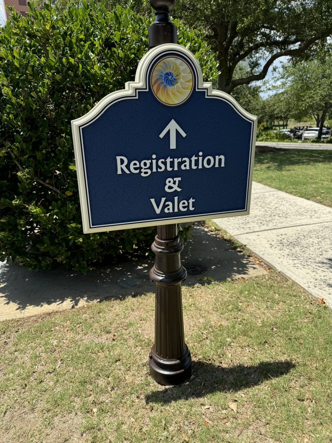Dark bronze 'Registration & Valet' custom wayfinding sign on an ornamental cast-iron post