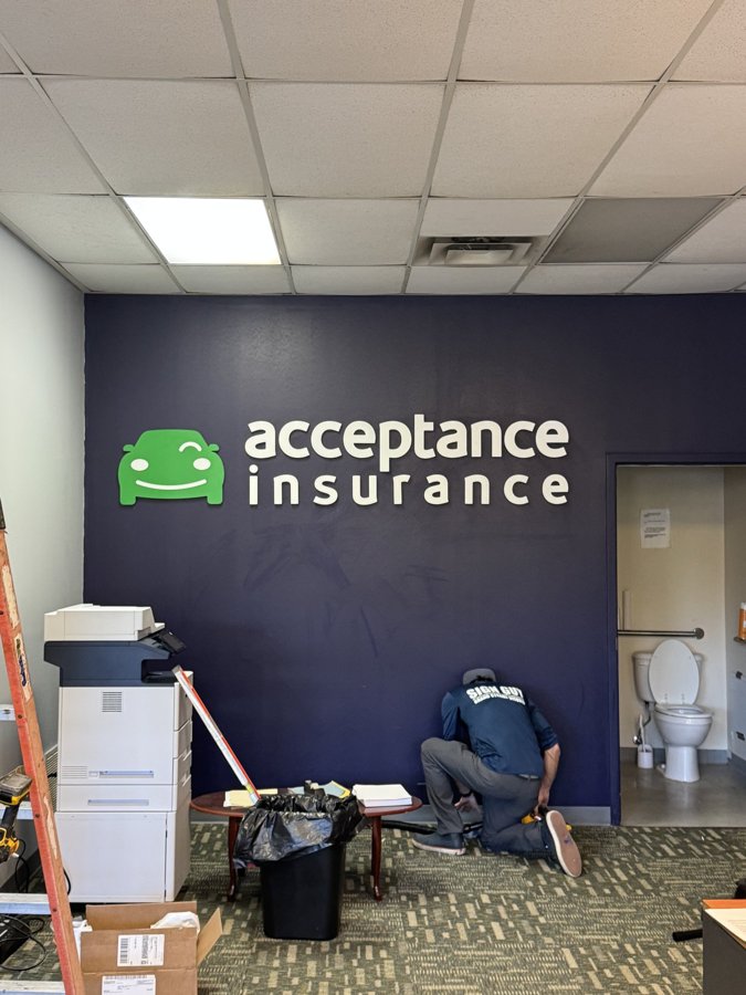 Interior view of Acceptance Insurance dimensional wall letters on a navy accent wall, install in-progress