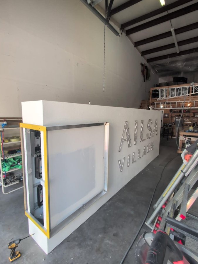 Ailsa Village dimensional sign mounted at reception, install day in-progress