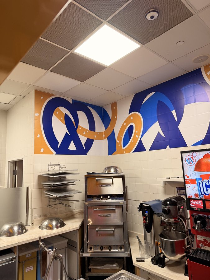 Auntie Anne's interior with printed pretzel-themed wall wrap and beverage station