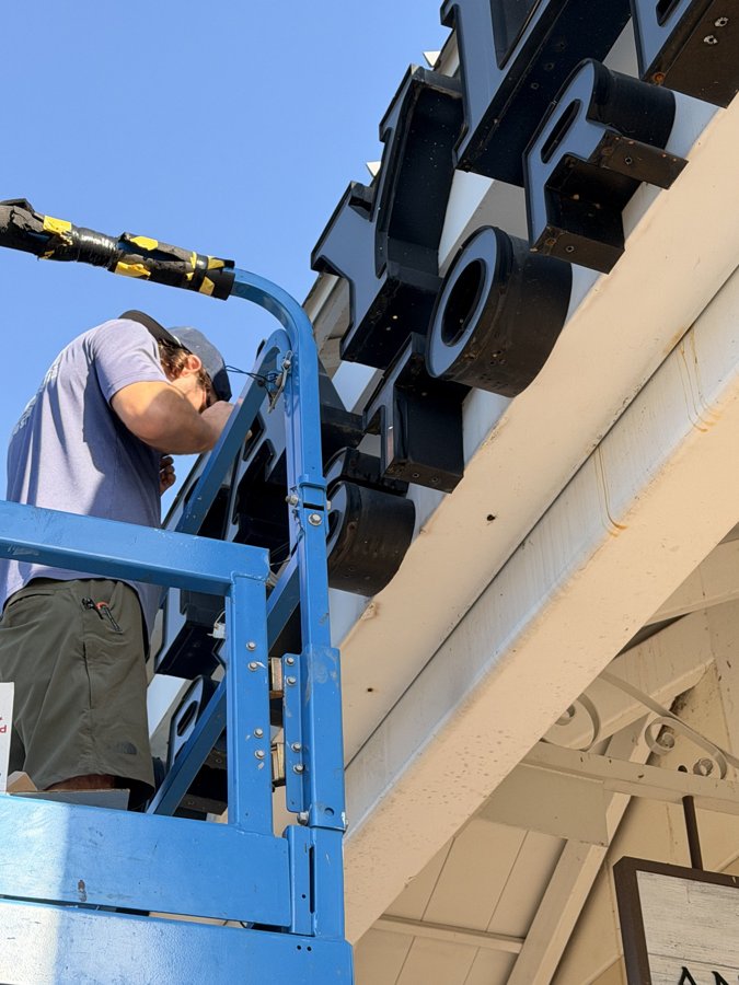 Installer working from a boom lift on a mall storefront sign