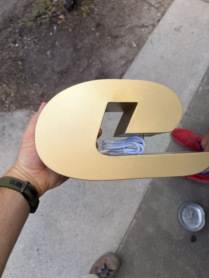 Gold letter "C" held up during fabrication with clean edges