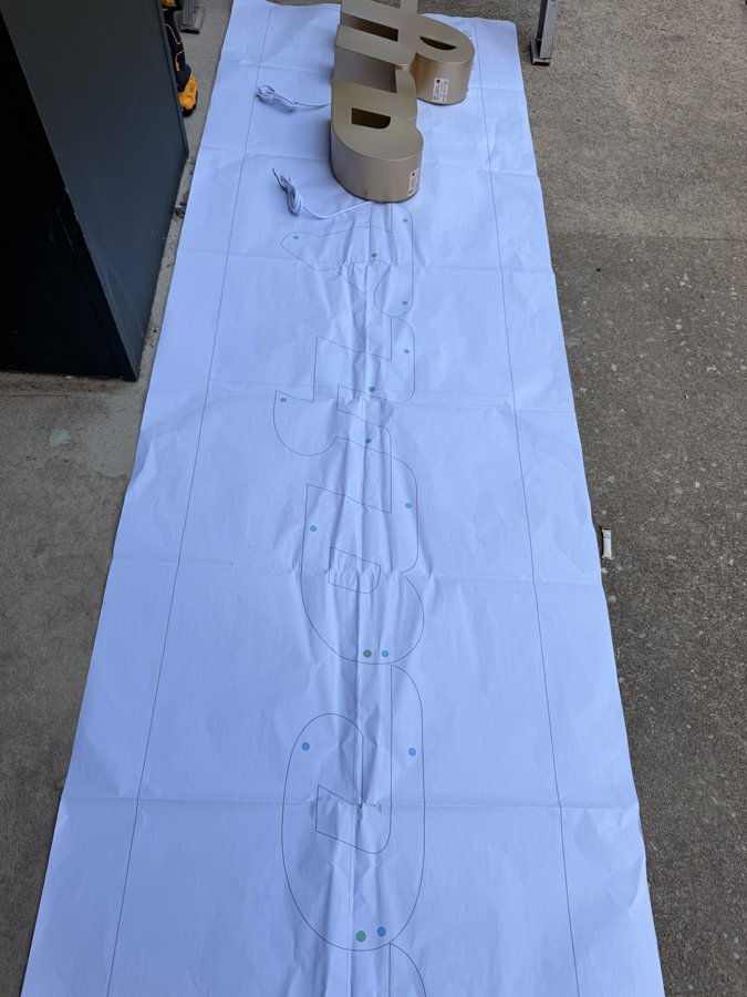 Gold letter positioned on paper template ready for wall install