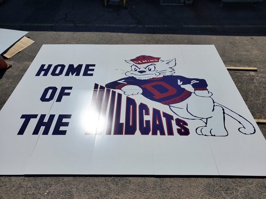 'HOME OF THE WILDCATS' large-format vinyl gym floor decal laid out before install